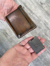 RCMP wallet coin showing size in man’s hand compared to leather wallet. RCMP wallet coin is approximately one quarter the size. 