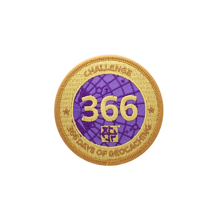 Patch with a gold background and a purple centre.  Over the purple it says 366.  Around the edge it says Challenge 366 Days of Geocaching.