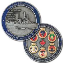 Picture of front and back of challenge coin.  It displays a ship on the front with a blue border, and 6 golden crests on the back, also surrounded by a blue border