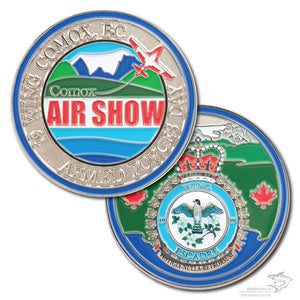 Comox Air Show coin, front and back, in polished silver with a Snowbird jet on the front, a crest with a printed bird on the back, with blues and greens and red writing
