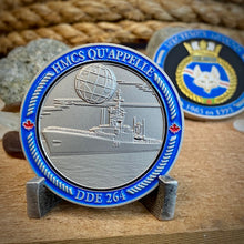 Back view of our HMCS Qu'Appelle challenge coin in a display stand. The coin displays the Qu'Appelle Ship in the water with a globe above it, all surrounded by a border with "HMCS Qu'Appelle" at the top, and "DDE 264" at the bottom