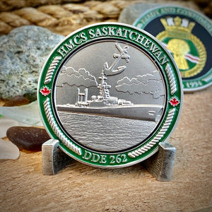 Back view of our HMCS Saskatchewan challenge coin in a display stand. The coin displays the Saskatchewan Ship in the water with an anchor above it, all surrounded by a border with "HMCS SASKATCHEWAN" at the top, and "DDE 262" at the bottom