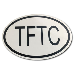 Oval bumper sticker that says "TFTC' In black on a white background 