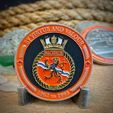 Front view of MacKenzie challenge coin in a display stand.The coin displays the Mackenzie Ship crest surrounded by a border with the phrase "By Virtue and Valour" at the top, and "1962 to 1993" at the bottom