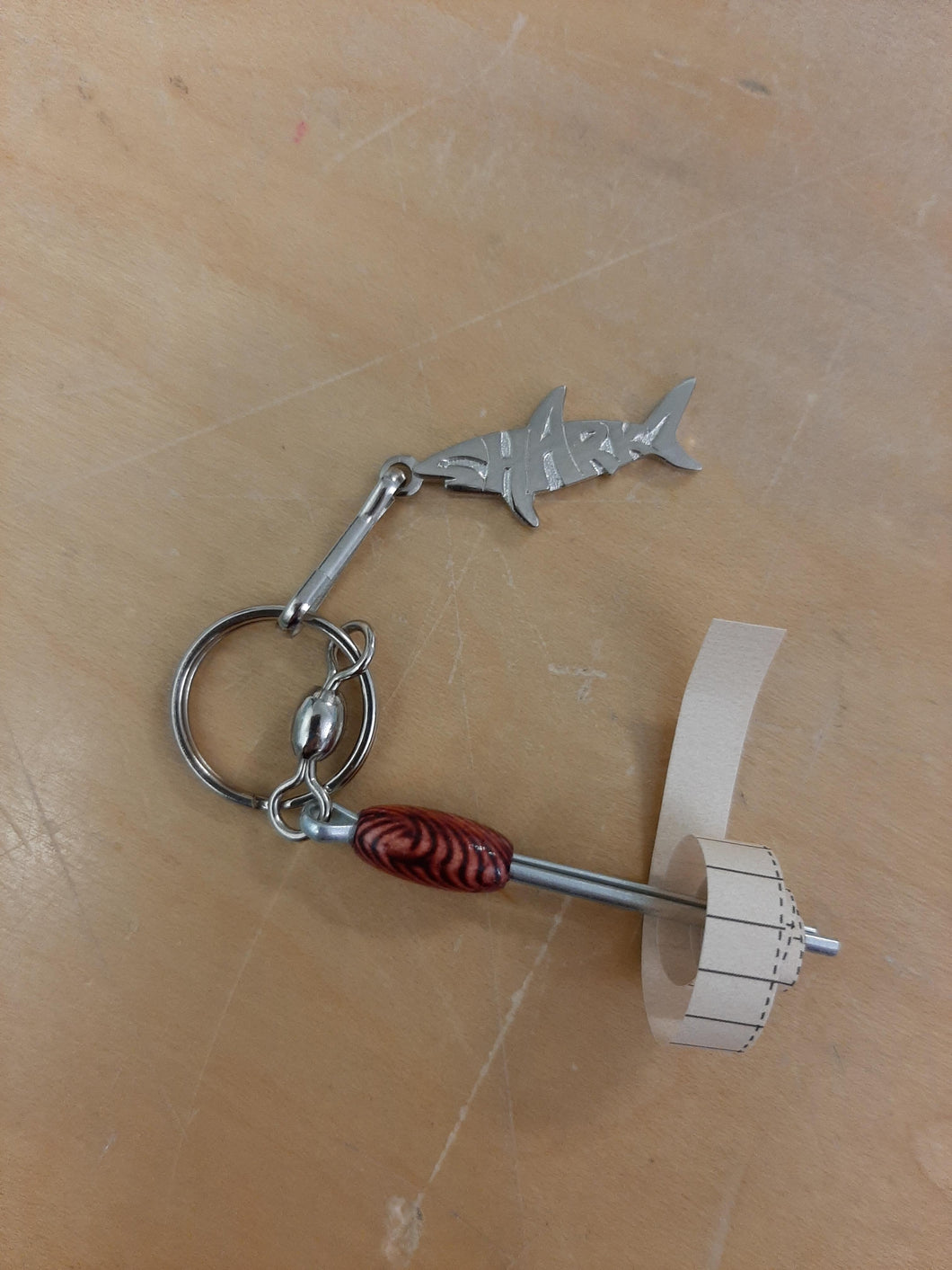 Silver Sharkz logo on a keychain with a nano log roller with a red bead