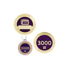 Milestone geocoin in gold with purple paint for your 3000th find.  Front and back pictured, as well as the matching tag.