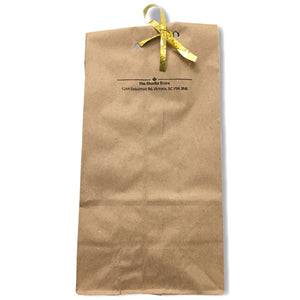 Brown paper bag with "The Sharkz Store" written on it, tied closed with a gold ribbon.
