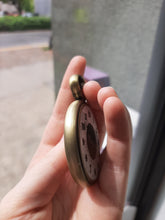 A side view of the Retirement Pocket Watch coin in someone's hand