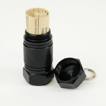 Black mighty-mini aluminum cache with logbook rolled up inside it