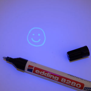 Edding 8280 UV Marker with UV light shining on it and a glowing happy face, drawn by the marker